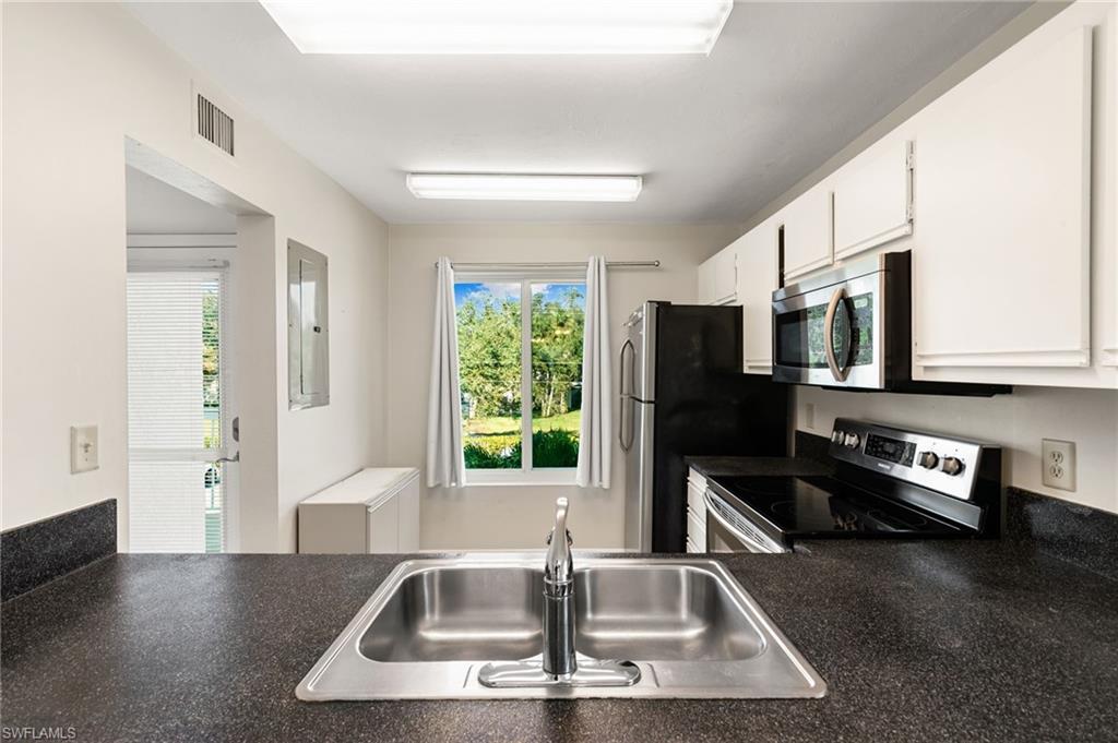 2149 San Marco Road, Unit 201 Marco Island, FL 34145 - Photo 7 of 22 a kitchen with stainless steel appliances a sink a stove a microwave a counter space and cabinets