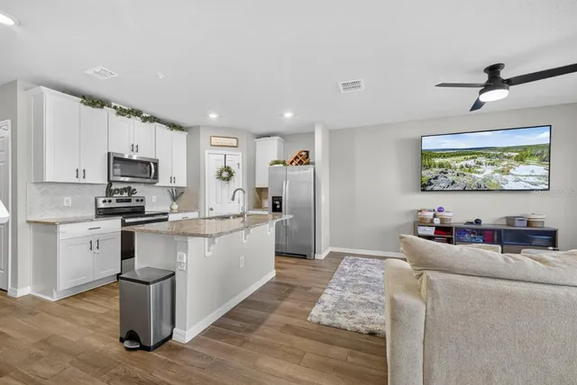 a kitchen with stainless steel appliances granite countertop a refrigerator a stove top oven a sink and dishwasher with wooden floor