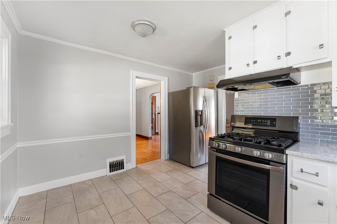 1623 Spangler Road Northeast Canton, OH 44714 - Photo 14 of 28 Kitchen with appliances with stainless steel finishes, white cabinets, ornamental molding, under cabinet range hood, and decorative backsplash