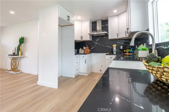 a kitchen with stainless steel appliances a sink a stove a refrigerator cabinets a dining table and chairs