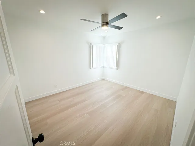 en empty room with wooden floor and ceiling fan