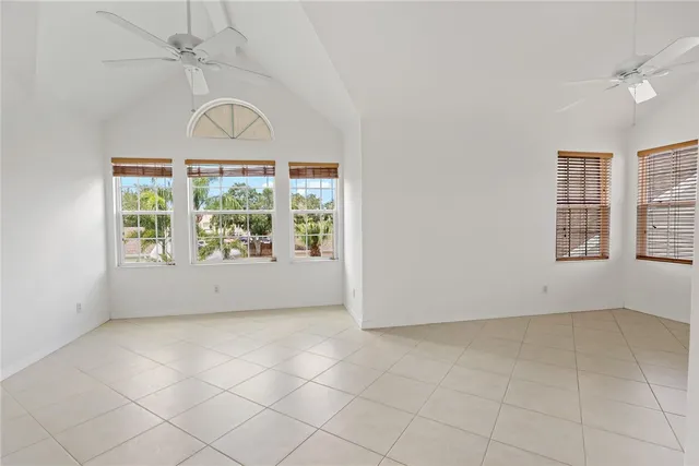 an empty room with windows and ceiling fan