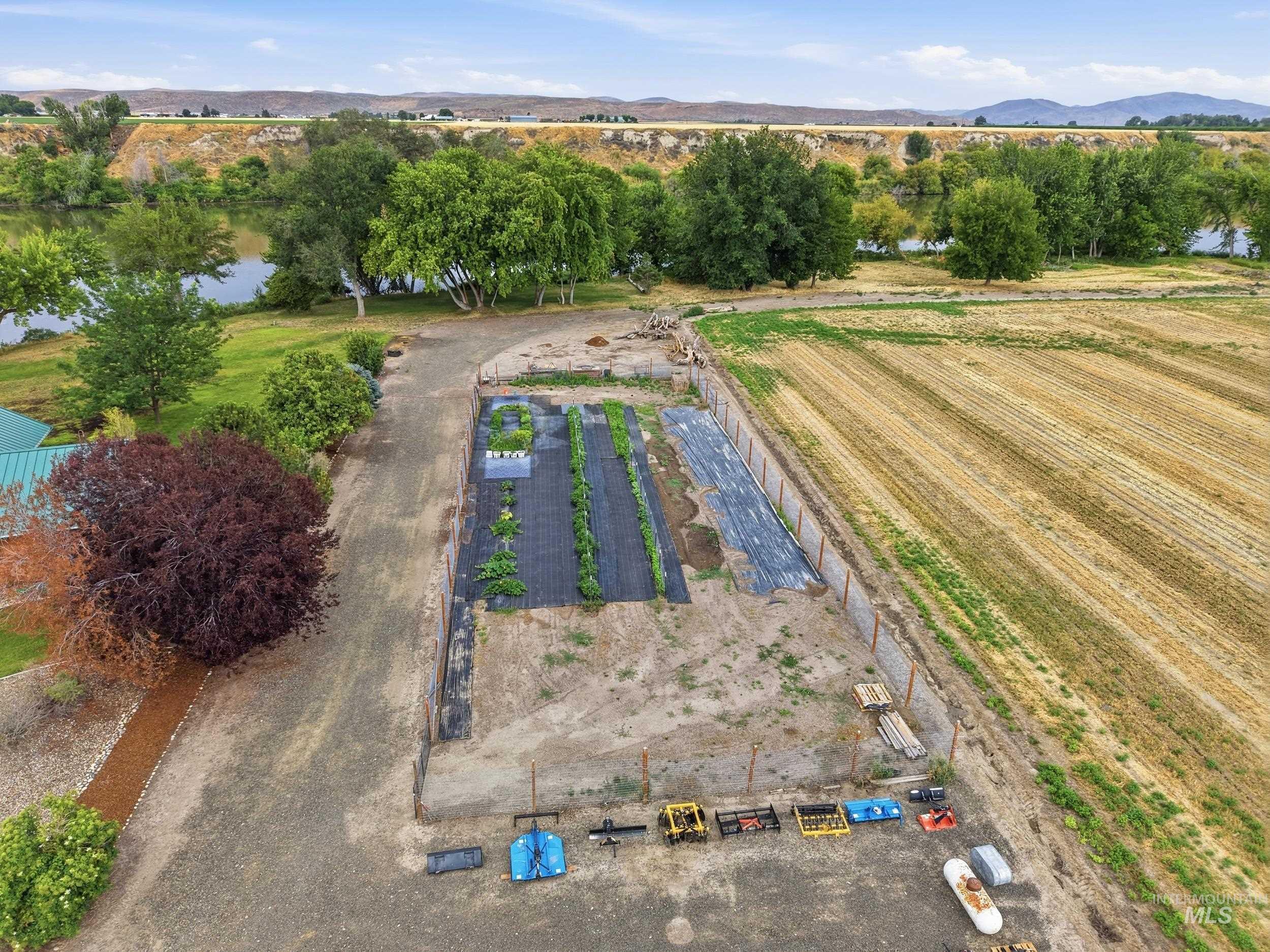 339 Airport Road Weiser, ID 83672 - Photo 43 of 49 Expansive agricultural land featuring a cultivated garden area, a large field with crop rows, and a riverfront boundary with mature trees
