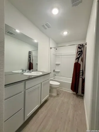 a bathroom with a granite countertop sink a toilet a mirror and shower