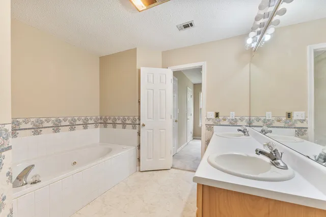 a view of a hallway with wooden floor and a bathroom