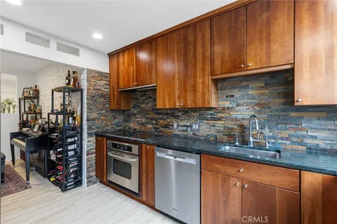 a kitchen with stainless steel appliances granite countertop wooden cabinets and a stove top oven