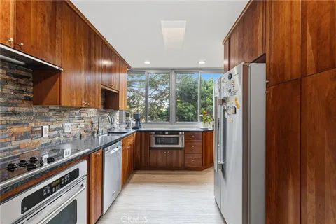 a kitchen with stainless steel appliances granite countertop a refrigerator a sink and wooden cabinets