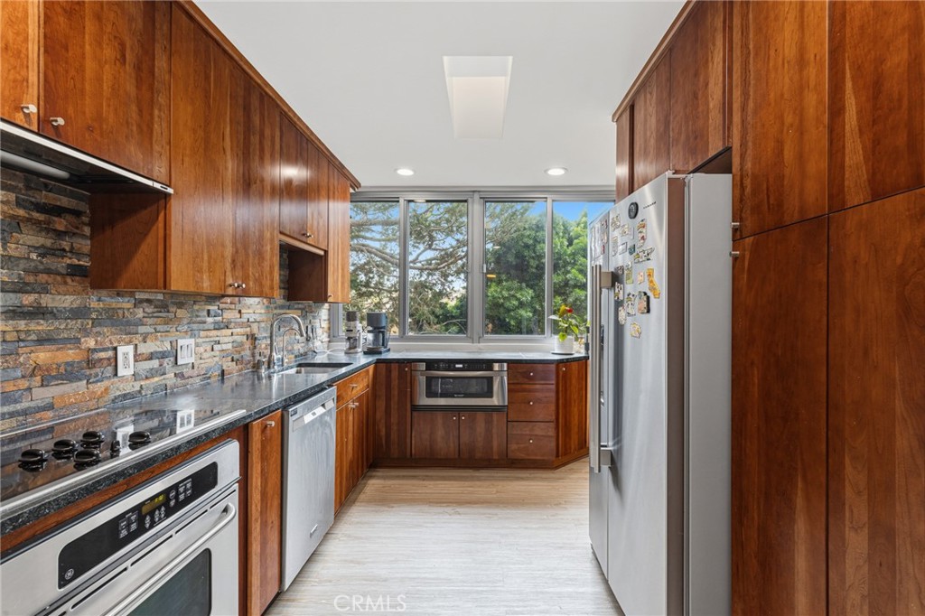 8701 Delgany Avenue, Unit 110 Playa del Rey, CA 90293 - Photo 3 of 22 a kitchen with stainless steel appliances granite countertop a refrigerator a sink and wooden cabinets