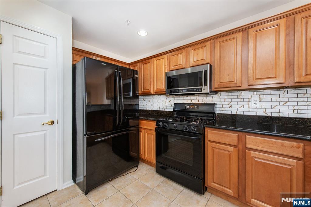 146 Summit Ridge, Unit 1406 Pompton Lakes, NJ 07442 - Photo 7 of 26 a kitchen with granite countertop wooden cabinets and stainless steel appliances