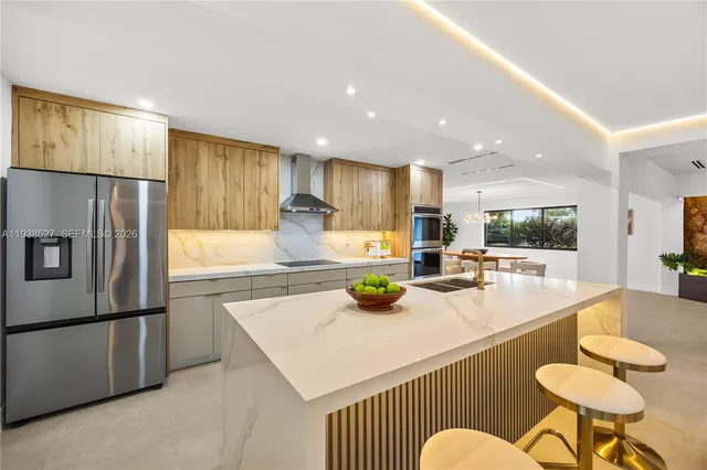 a kitchen with stainless steel appliances granite countertop a refrigerator a stove a sink a dining table and chairs with wooden floor