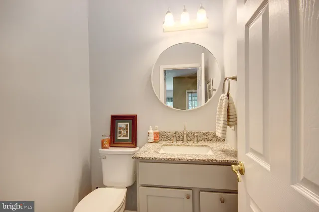 a bathroom with a granite countertop toilet sink and mirror
