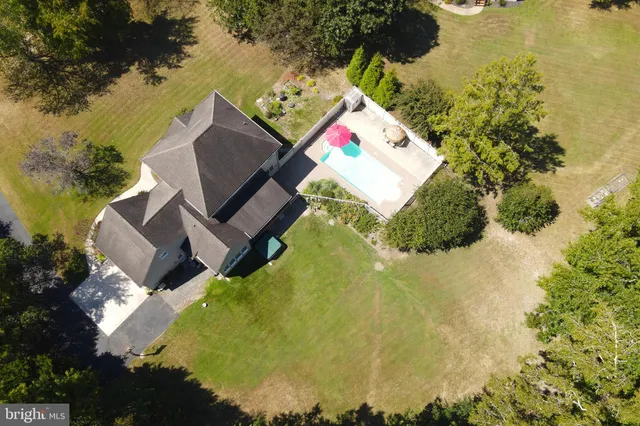 an aerial view of a house with swimming pool and large trees