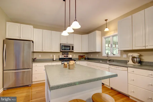 a kitchen with stainless steel appliances granite countertop a sink a stove a refrigerator cabinets and chairs
