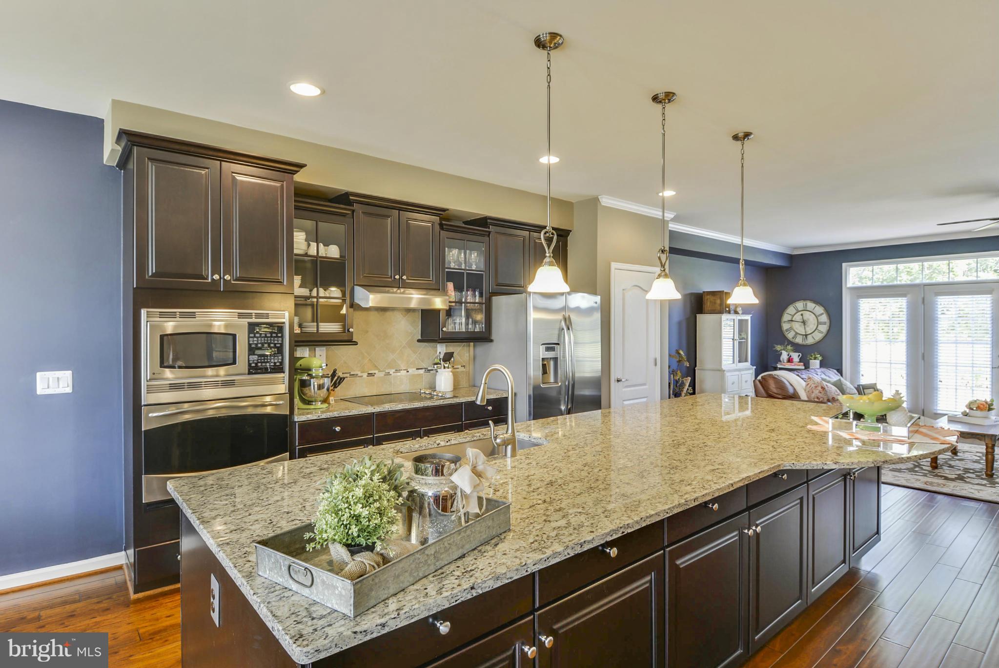 a view of a kitchen with kitchen island a counter top space a sink stainless steel appliances and cabinets