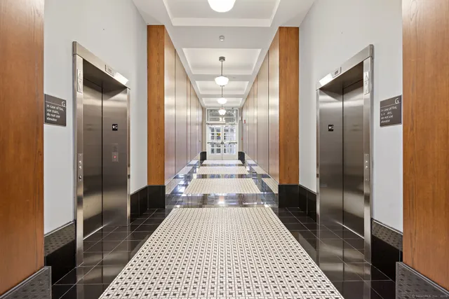 a view of a hallway with wooden floor and a bathroom
