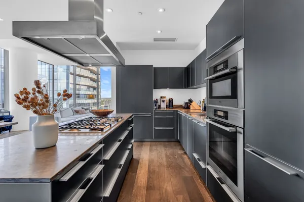 a kitchen with stainless steel appliances granite countertop a stove top oven a sink dishwasher a dining table and chairs with wooden floor