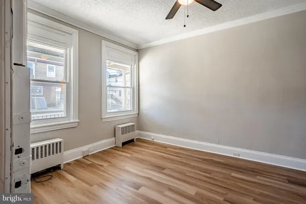 a view of an empty room with a window and wooden floor