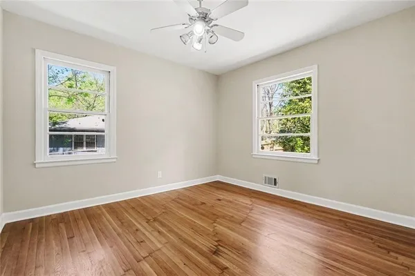 a view of an empty room with wooden floor and a window