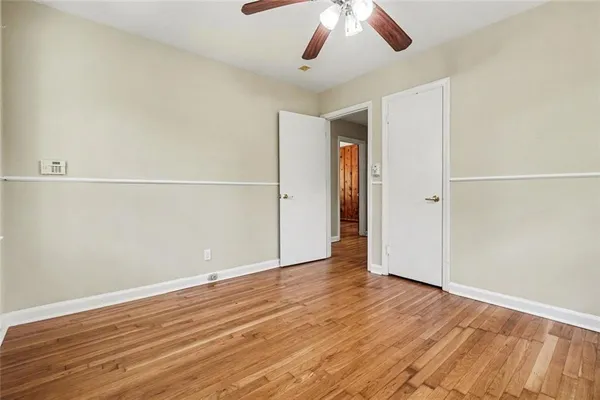 an empty room with wooden floor chandelier fan and closet