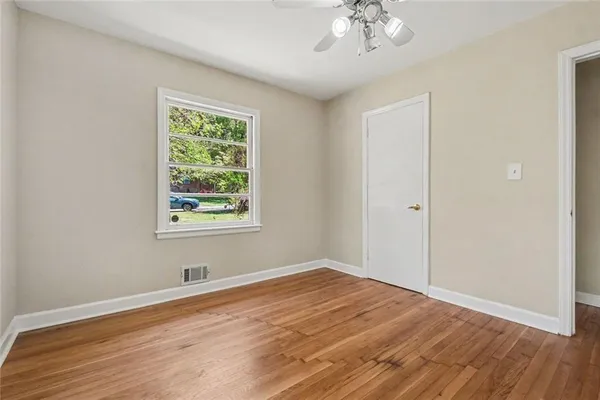 a view of empty room with wooden floor and fan