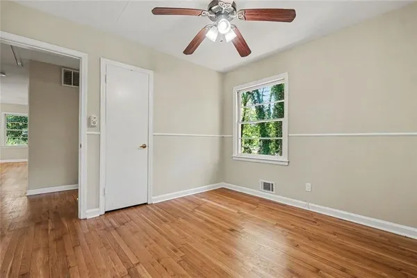 a view of an empty room with wooden floor and a window