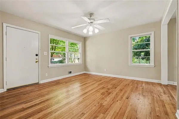a view of an empty room with wooden floor and a window
