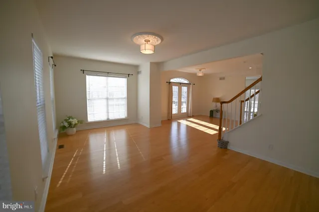 a view of an empty room with window and wooden floor