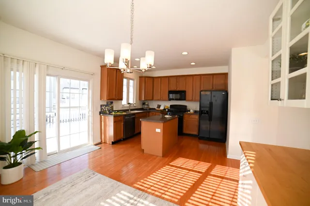 a kitchen with stainless steel appliances kitchen island granite countertop a refrigerator a sink dishwasher a stove and a dining table with wooden floor