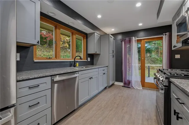 a large kitchen with stainless steel appliances granite countertop a stove a sink and a large window