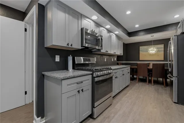 a kitchen with stainless steel appliances granite countertop a stove a sink and a microwave