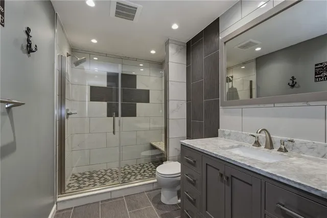 a bathroom with a granite countertop sink a toilet a mirror and shower