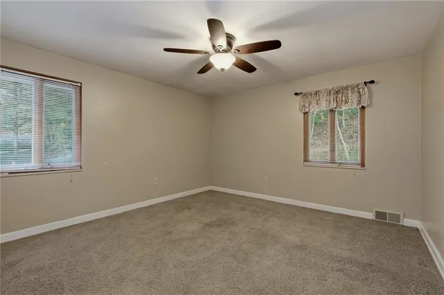 an empty room with window and ceiling fan