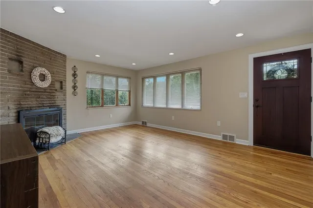 a view of an empty room with window and wooden floor