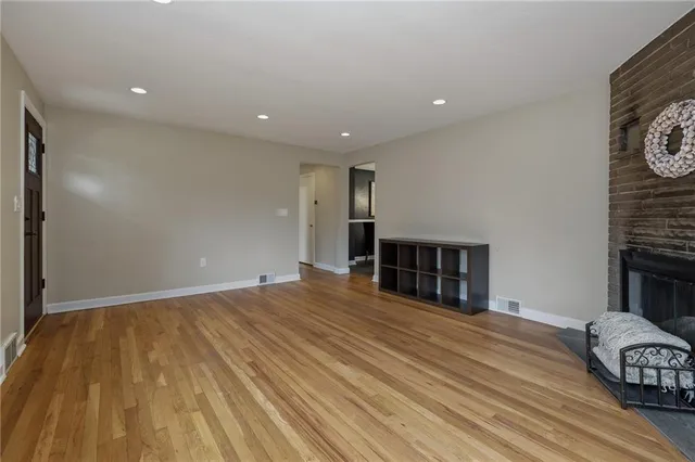 a view of a livingroom with wooden floor and a fireplace