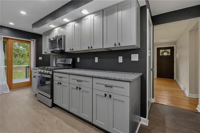 a kitchen with stainless steel appliances granite countertop a stove a sink and a microwave