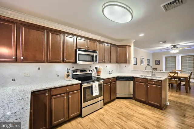 a kitchen with stainless steel appliances granite countertop a sink stove cabinets and refrigerator