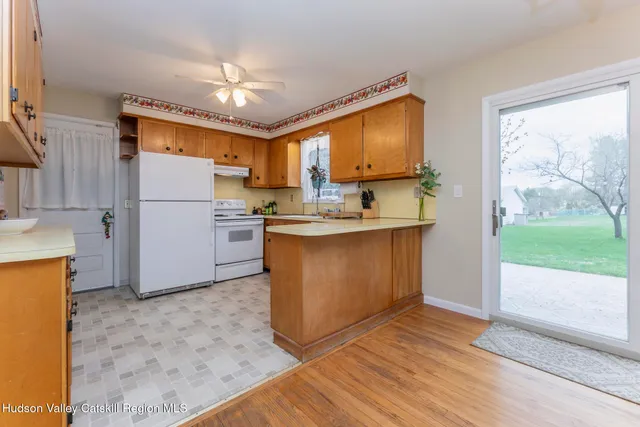 a kitchen with kitchen island a stove a refrigerator a sink and a dining table with wooden floor