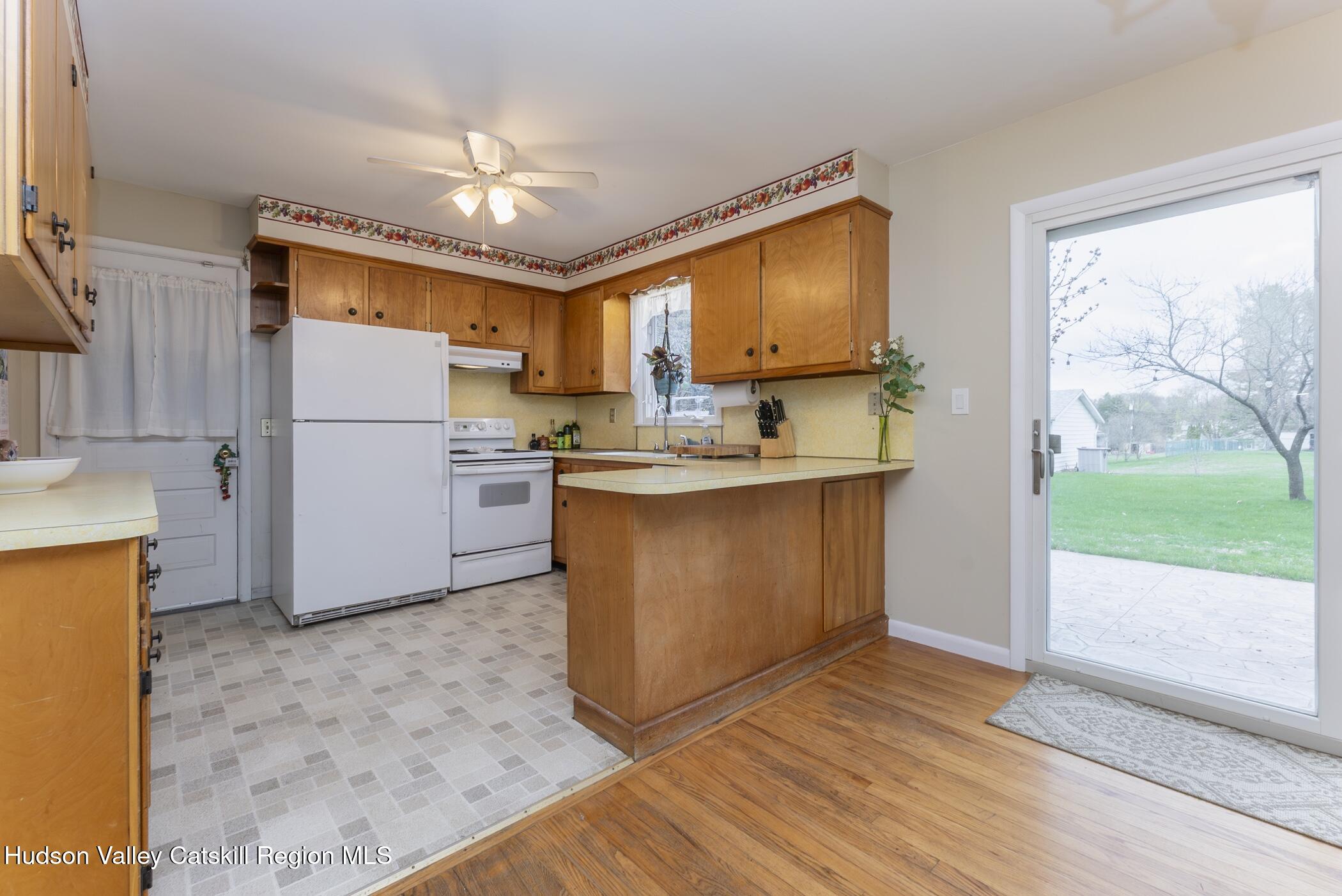 121 Rayna Street Hurley, NY 12443 - Photo 14 of 41 a kitchen with kitchen island a stove a refrigerator a sink and a dining table with wooden floor