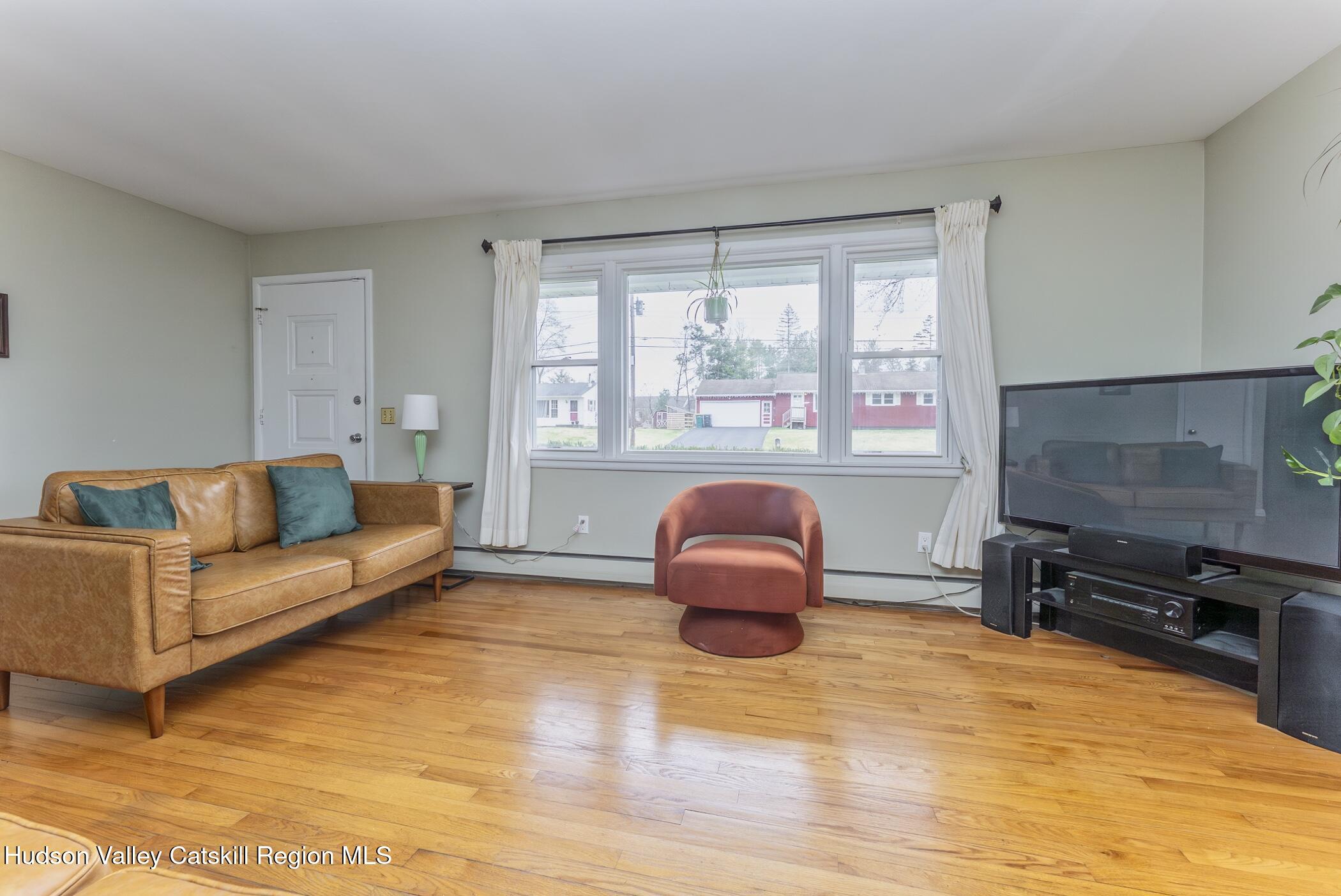 121 Rayna Street Hurley, NY 12443 - Photo 8 of 41 a living room with furniture a flat screen tv and a floor to ceiling window