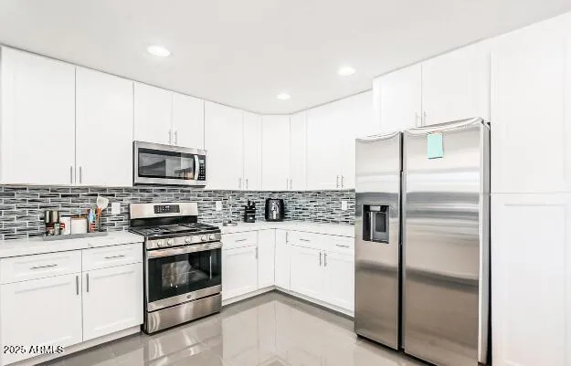 a kitchen with white cabinets and stainless steel appliances