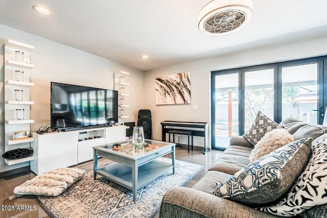 a living room with furniture a flat screen tv and a large window