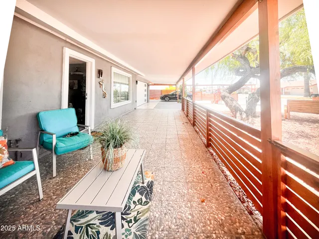 a porch with a table and chairs next to a large window
