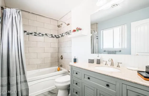 a bathroom with a granite countertop sink a toilet a mirror a vanity a bathtub and shower