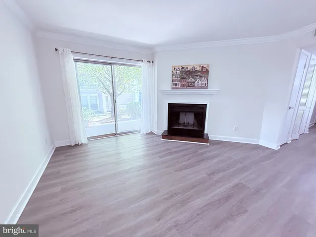 an empty room with wooden floor fireplace and windows