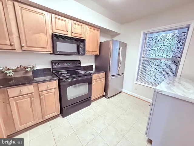 a kitchen with granite countertop a refrigerator stove top oven and sink