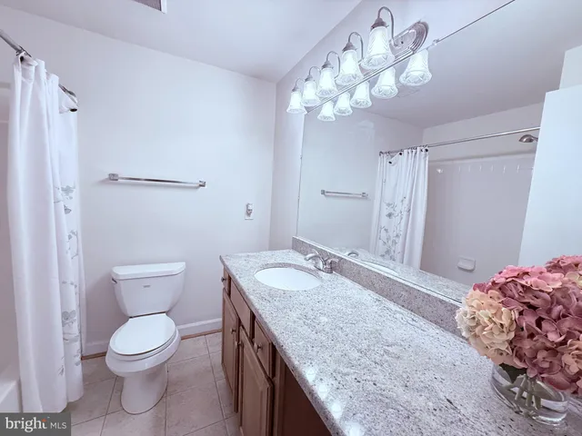 a bathroom with a granite countertop sink toilet a mirror and shower