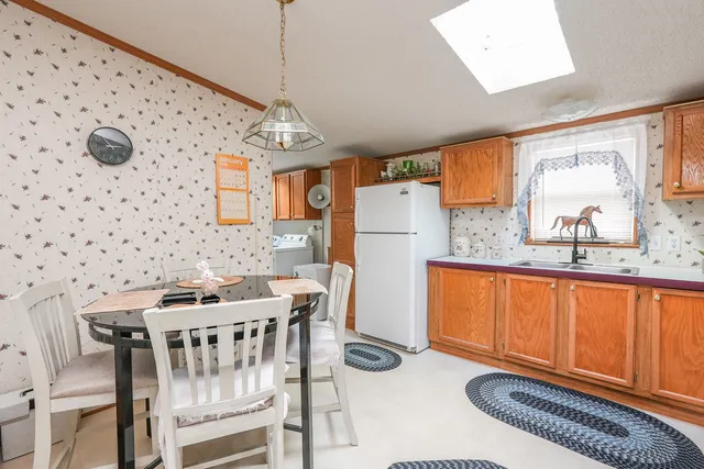 a dining room with stainless steel appliances a dining table chairs and a refrigerator a sink dishwasher with wooden floor