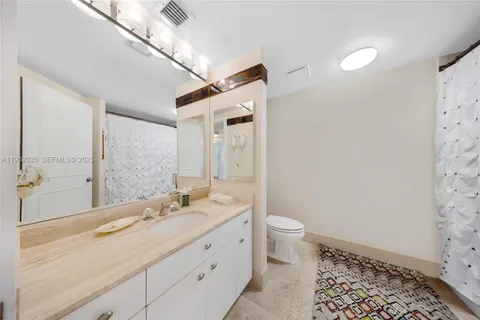 a spacious bathroom with a granite countertop sink a toilet a mirror and shower