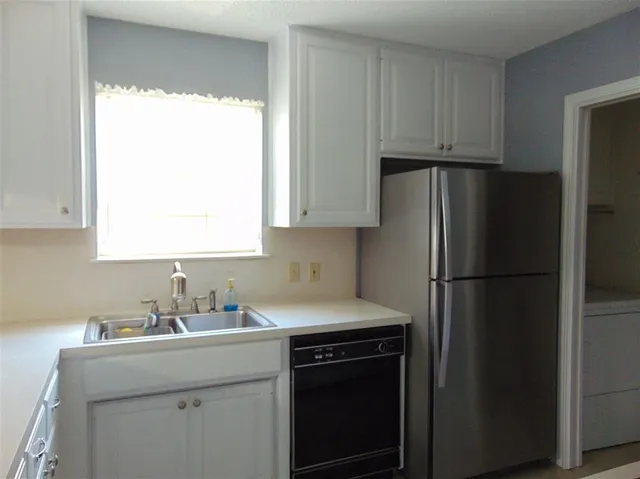 a kitchen with a refrigerator sink and cabinets