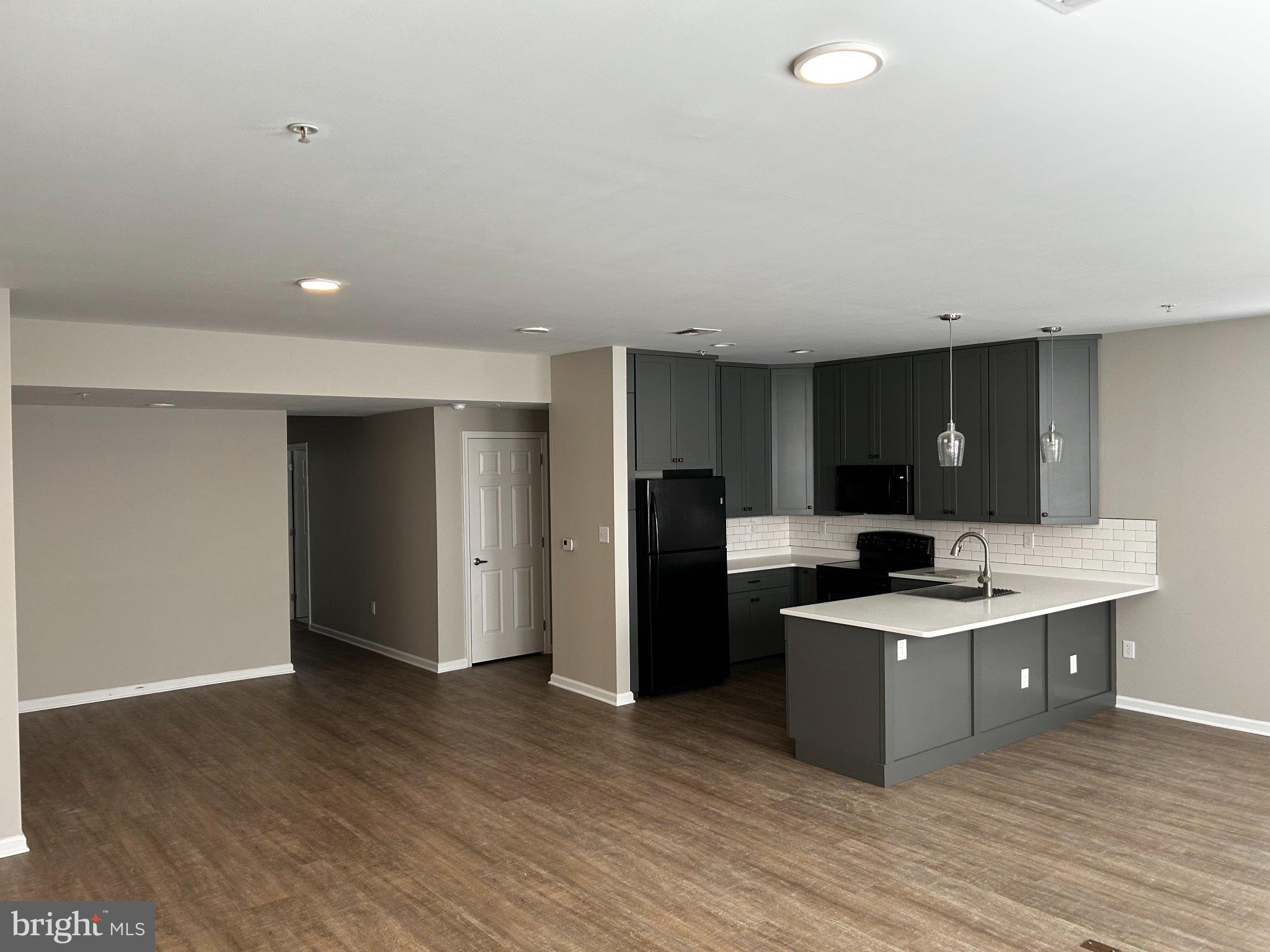 134 Bridge Street, Unit 201 Phoenixville, PA 19460 - Photo 10 of 12 a kitchen with stainless steel appliances kitchen island granite countertop a refrigerator and a sink
